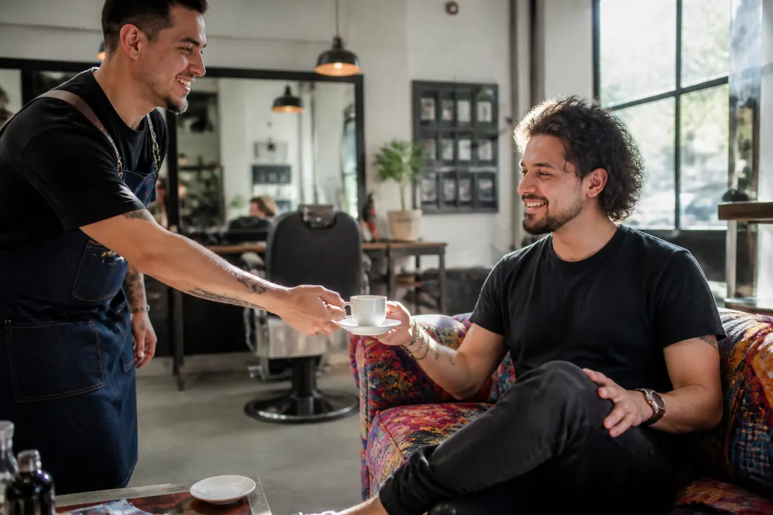 Barbeiro servindo café a um cliente na sala de espera