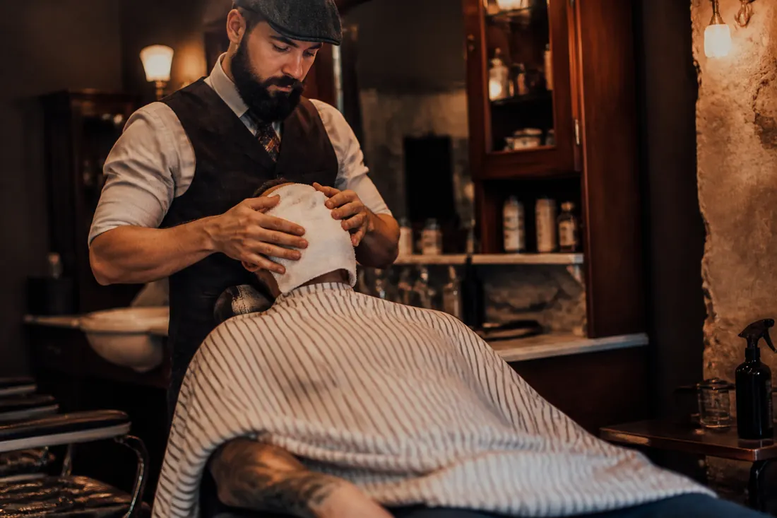Neto fazendo a barba de um cliente com toalha quente
