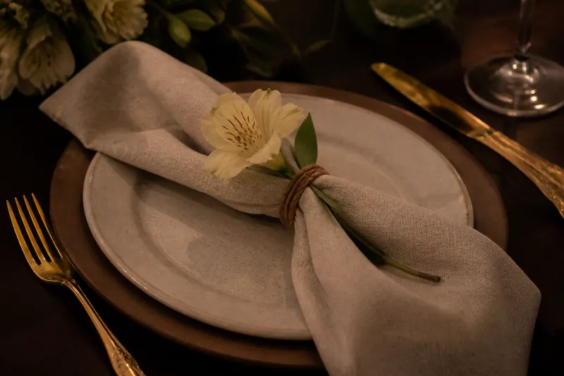 Detalhe da mesa posta com talheres dourados