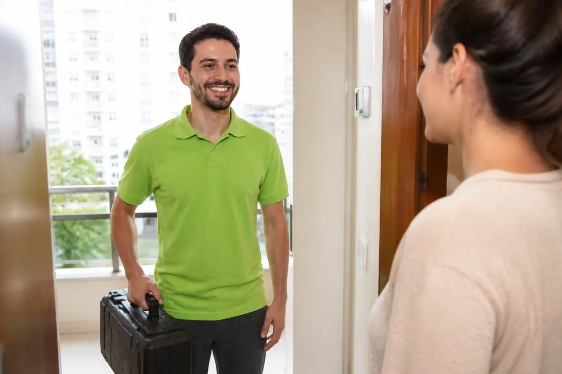 Técnico com maleta de equipamentos sendo recebido na porta de um apartamento