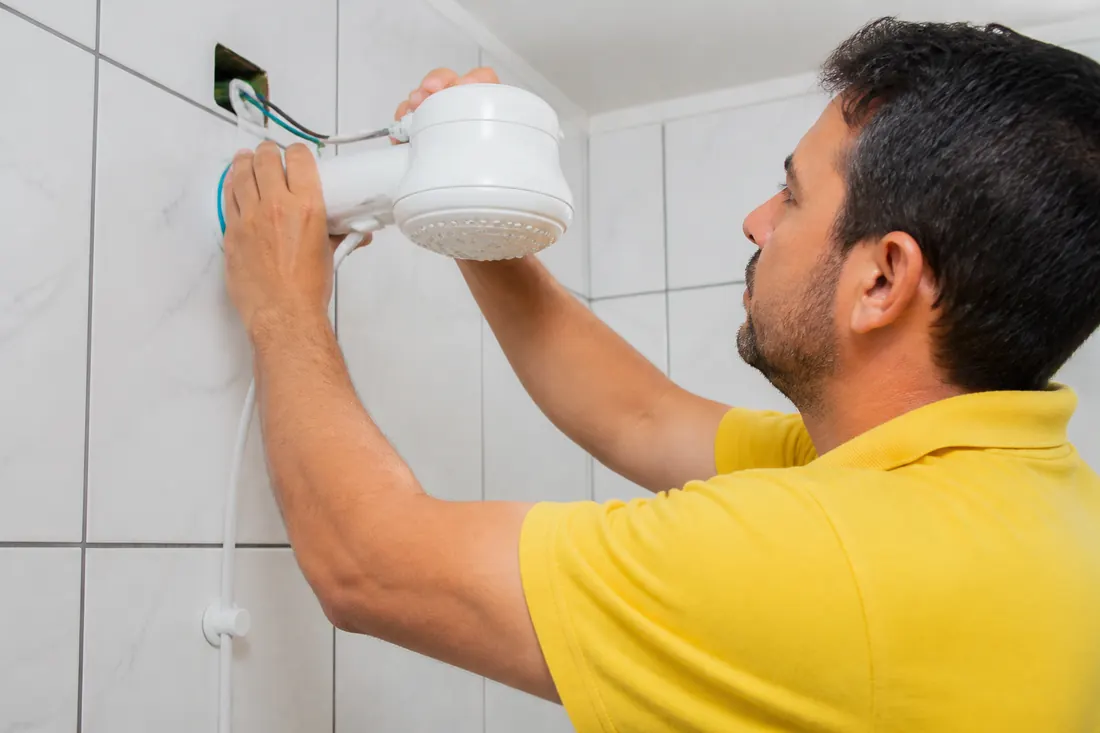 Eletricista instalando um chuveiro elétrico em um banheiro