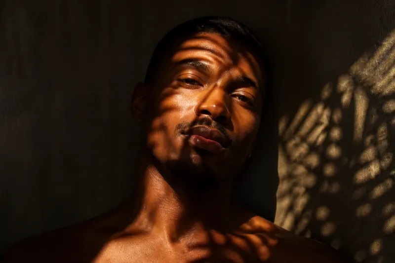 Retrato de homem com sombras de folhas no rosto