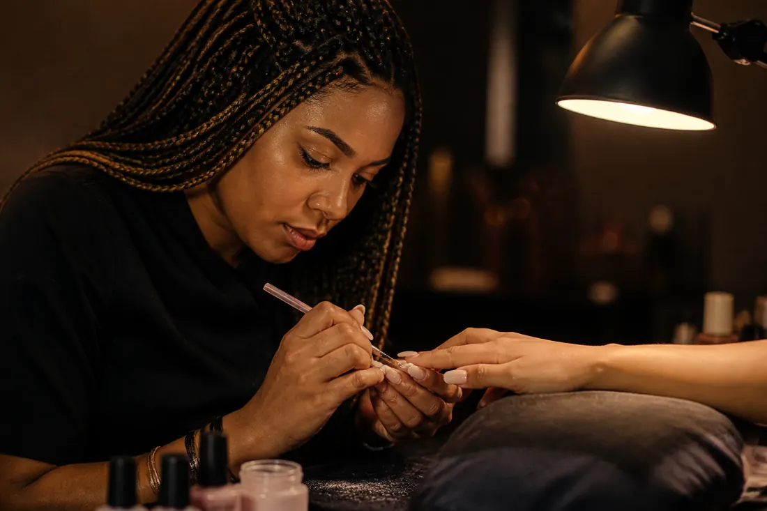 Juliana esculpindo unhas em gel na mão de uma cliente